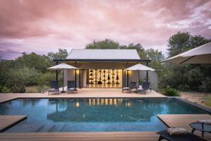 a villa with a swimming pool at dusk at Ujima Lodge in Hoedspruit