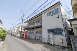 an empty street with a white building with a balcony at KEI HOUSE Yamato 202 in Yamato