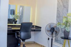 a desk with a chair and a fan in a room at Henry George Hotel Ltd in Idimu