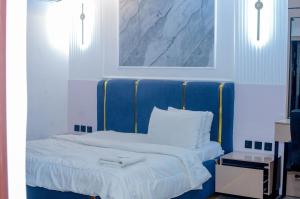 a bed with a blue headboard in a room at Henry George Hotel Ltd in Idimu
