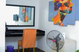 an orange chair and a fan in a room at Henry George Hotel Ltd in Idimu