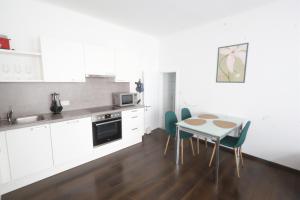 a kitchen with white cabinets and a table and chairs at Appartementhaus Ludwig in Mörbisch am See