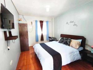a bedroom with a bed and a flat screen tv at Marias's Inn in Pooc