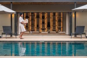 a woman walking next to a swimming pool at Ujima Lodge in Hoedspruit