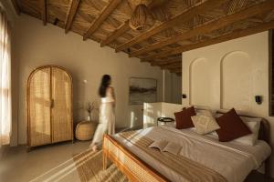 a woman is standing in a bedroom with a bed at Native Villa with Pool at Kalumo Lodge in Oslob