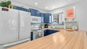 a kitchen with blue cabinets and a white refrigerator at Daylight Cove Lakefront Chic in Lake Ozark +27 photos