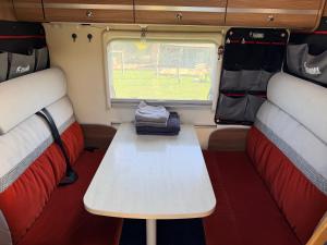 a room with two seats and a table in a rv at Obytňák Bohoušek in Pulečný
