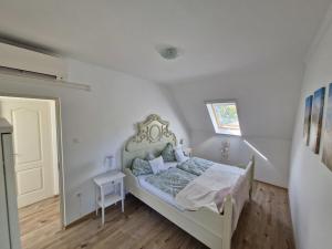 a white bedroom with a bed and a window at Fenyves Ferienhaus 1 **** in Balatonfenyves
