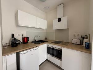 a kitchen with white cabinets and a wooden counter top at La Ferronnerie Cassis centre in Cassis