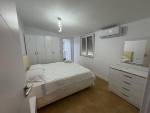 a white bedroom with a bed and a mirror at Grand House Apartment in Selitë e Vogël