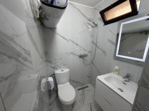 a white bathroom with a toilet and a sink at Grand House Apartment in Selitë e Vogël +28 photos