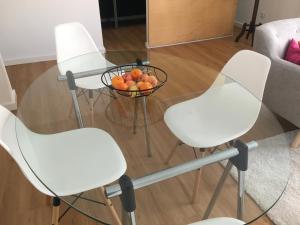 four white chairs and a glass table with a bowl of fruit at Casa Pedra do Sal in Estoril