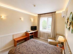 a hotel room with a bed and a desk and a television at Hotel Cheap - Smart choice - Great value in Sofia