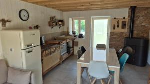 a kitchen with a table and a white refrigerator at La cabane du pédaleur in Fourbanne