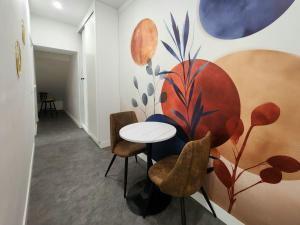 a table and chairs in a room with a painting on the wall at Le Tom de Libourne in Libourne