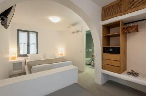 a white bedroom with a bed and a bathroom at Nissia Kamares in Kardamaina