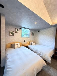 two beds in a room with a window at 奄美 Palm Tree Terrace in Ōkachi