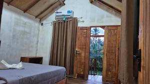 a bedroom with a bed and a door with a window at Arsilahomestay in Tetebatu