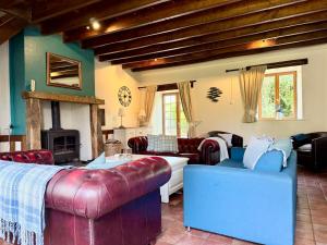 a living room with leather furniture and a fireplace at La Cahudiere in Saint-Martin-Landelles