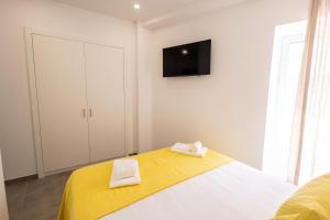 a bedroom with a bed with yellow sheets and a tv on the wall at lovely cityscape in Lagos +113 photos