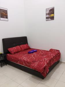 a bed with a red comforter and a bottle on it at Yashz Guest House in Port Dickson