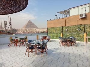 a group of tables and chairs on a roof with the pyramids at Basha Pyramids Best View in Giza