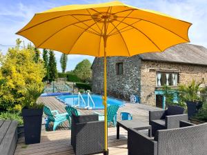 a yellow umbrella sitting on a deck next to a pool at La Cahudiere in Saint-Martin-Landelles