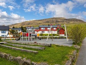 a playground in a town with a hill in the background at Beachhouse Syðrugøta in Syðrugøta