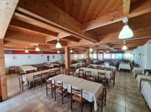 a dining room with tables and chairs and wooden ceilings at Hotel Paolino in Cavareno