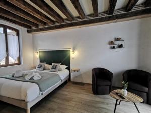 a bedroom with a large bed and two chairs at Les Nuitées de Bois Renaud Chambre d'Hôtes LA FORET in Marcilly-en-Gault