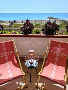 two chairs and a table with wine glasses on a balcony at Studio Vue mer, Piscine, Wifi, Climatisation, Parking privé, Terrasse 1ère ligne - La Coulée Douce in Frontignan