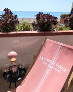 a table with wine glasses and a sign on a balcony at Studio Vue mer, Piscine, Wifi, Climatisation, Parking privé, Terrasse 1ère ligne - La Coulée Douce in Frontignan