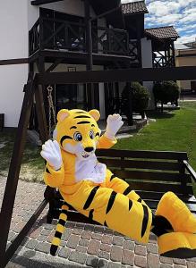 a large tiger mascot sitting on a swing at Arena Slonca in Łeba