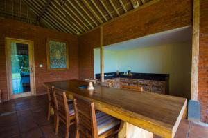 uma sala de jantar com uma grande mesa de madeira e cadeiras em Suarti Boutique Village em Ubud