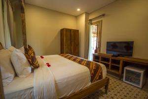a bedroom with a bed and a flat screen tv at Suarti Boutique Village in Ubud