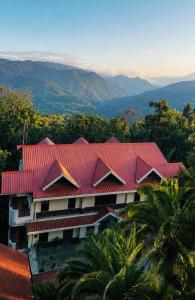 a building with a red roof with mountains in the background at Kalimpong Bungalow in Kalimpong