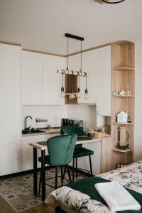 a kitchen with white cabinets and a table and chairs at D Mol Studio apartman in Tuzla
