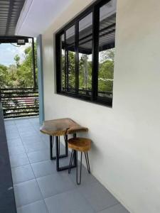 a table and stool in a room with windows at A&E Transient Rooms in Calatagan
