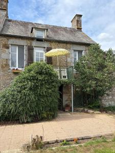 a brick house with an umbrella in front of it at 11 Steps Rustic Charming Flat in Normandy in Aubusson