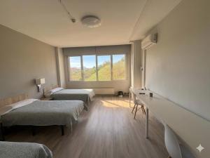 a room with three beds and a window at Residencia Albergue Jaca in Jaca +39 photos