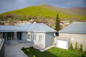 a white house with a mountain in the background at Casa Serena Sheki in Sheki