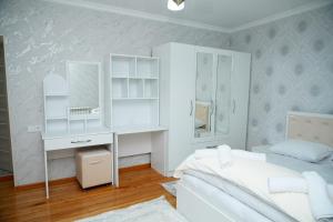 a white bedroom with a bed and a desk and mirror at Casa Serena Sheki in Sheki