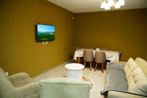 a living room with a table and a tv on the wall at Casa Serena Sheki in Sheki
