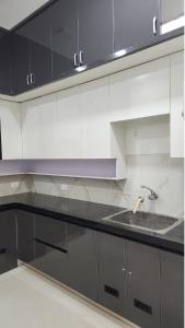 a kitchen with black and white cabinets and a sink at Holiday Home Madurai - Duplex Villa Umachikulam in Madurai