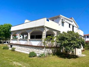 a white house with a tree in front of it at Apartman Luka in Pinezici