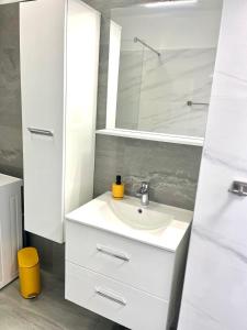 a white bathroom with a sink and a mirror at Apartman Luka in Pinezici