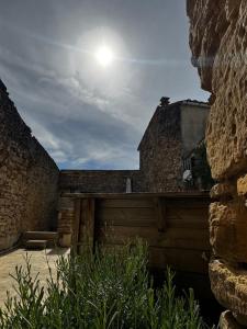 a stone building with a gate and the sun in the sky at Maison de Village 4 chambres in Sabran