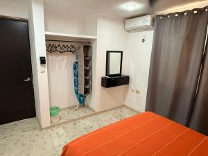 a bedroom with an orange bed and a closet at Casita Escondida in Mérida