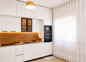 a kitchen with white cabinets and a sink and a window at Sea View Borsh Albania in Borsh +23 photos