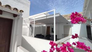 a white house with pink flowers on the balcony at Hogar de la plata in Sanlúcar de Barrameda